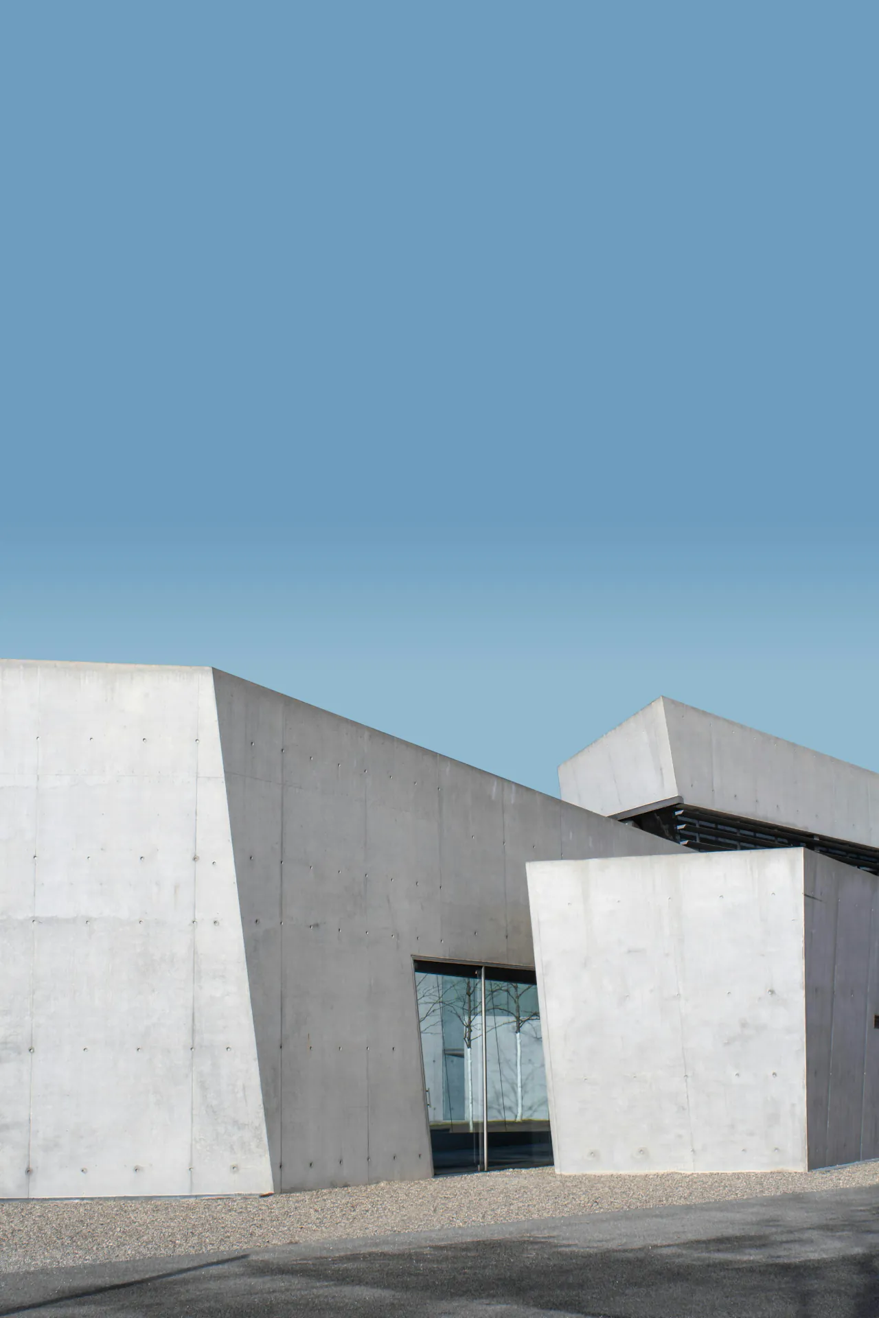 An angular white concrete building under a clear blue sky