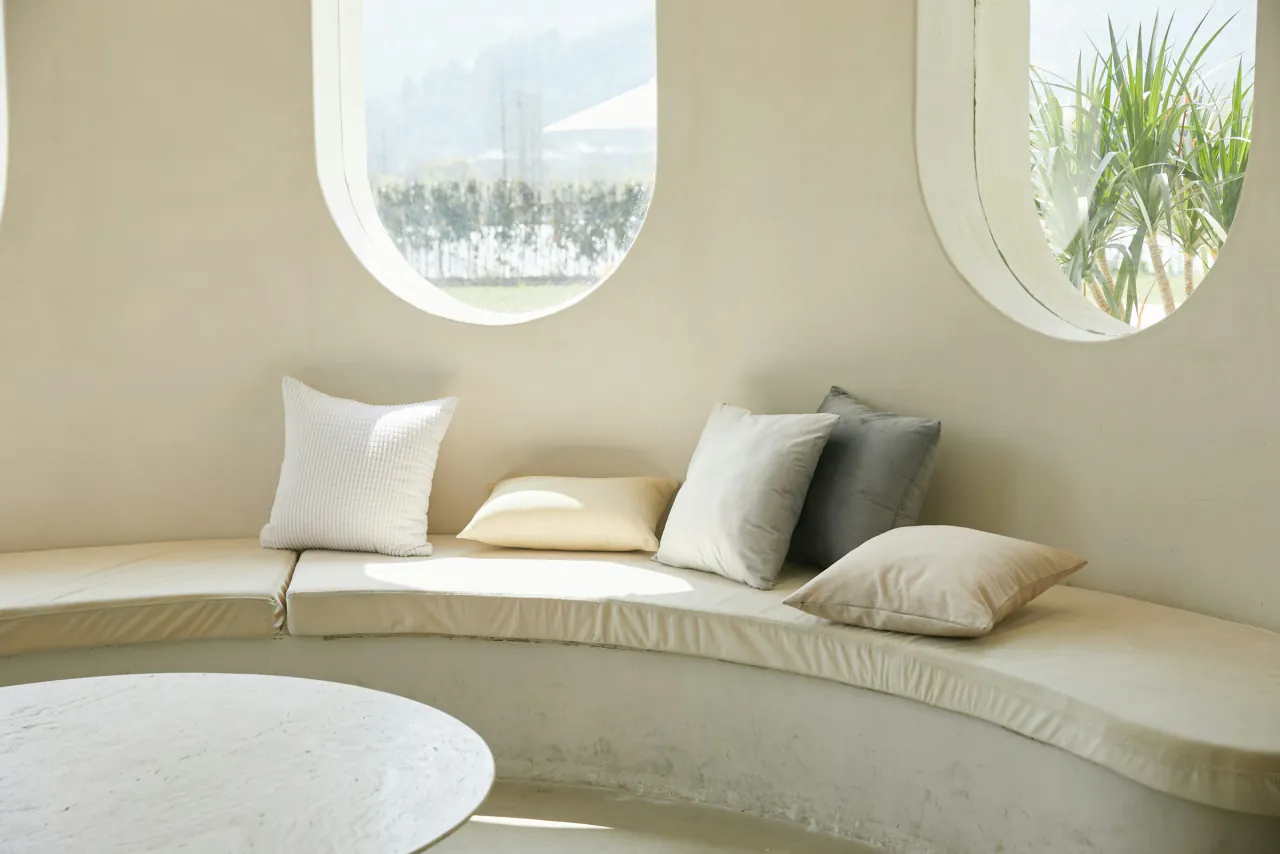 A curved bench with cushions beneath two oval windows